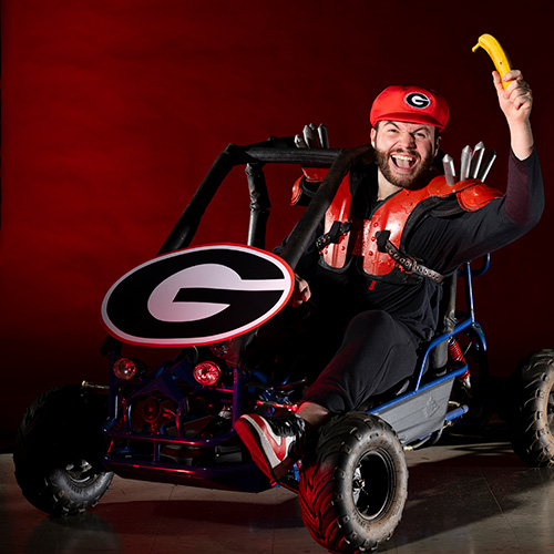Austin Rogers sitting in a Mario-Kart-style go-kart holding a banana