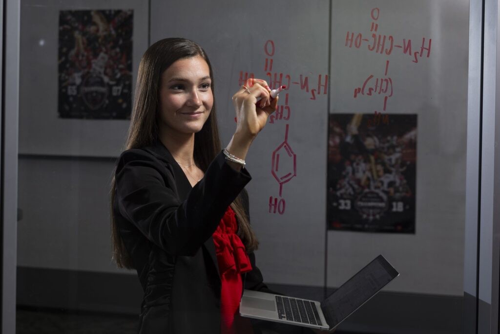 Portrait of athletics tutor, senior Halle Bynum writing equations on the glass of a study room at the Rankin Smith Student Athlete Academic Center.