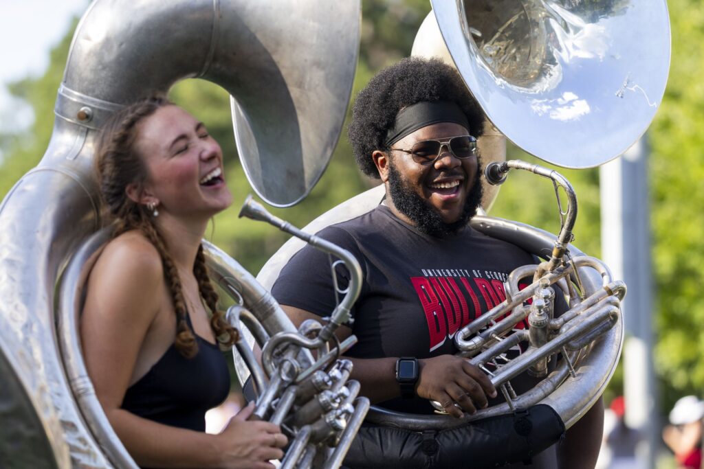 (L-R) Tuba player Lorelai Crook shares a laugh with Travis Mansfield while on a break during Redcoat Marching Band practice at the Redcoat Marching Band Practice Field.