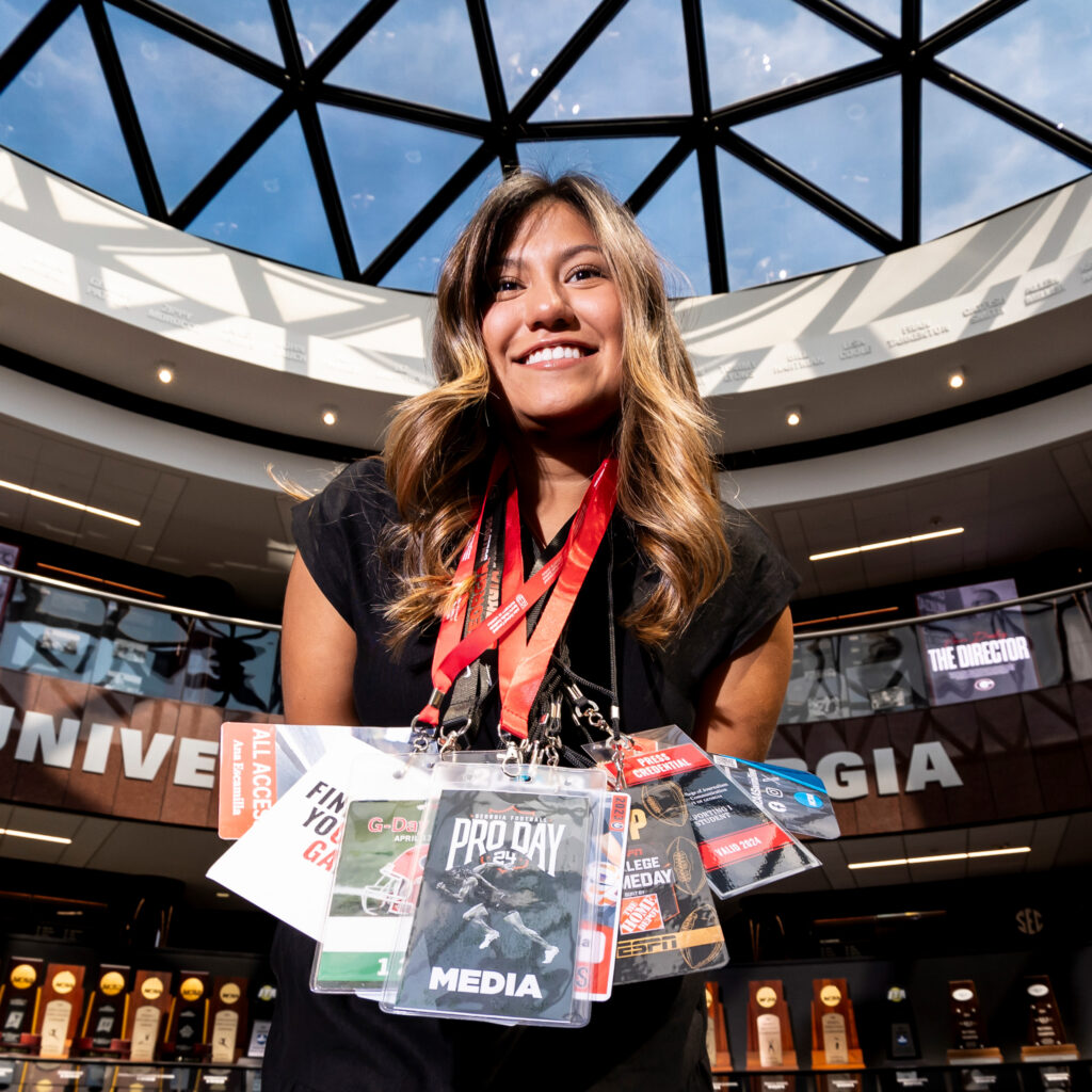 Portrait of Ana Escamilla holding all of her game day badges.