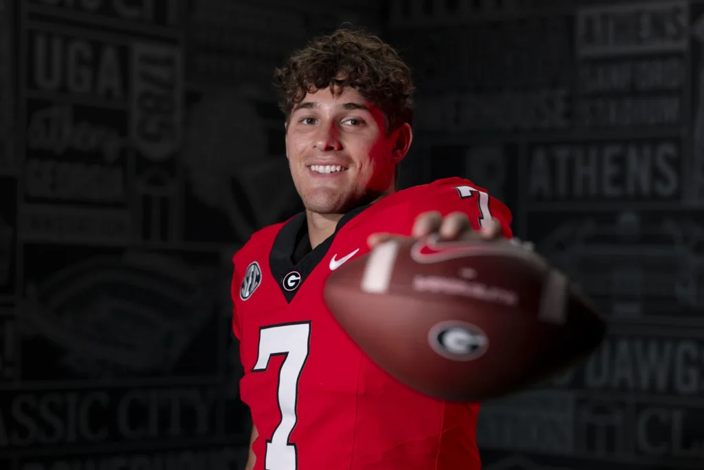 Luckie Lawson in his football uniform holding the football in front of him.