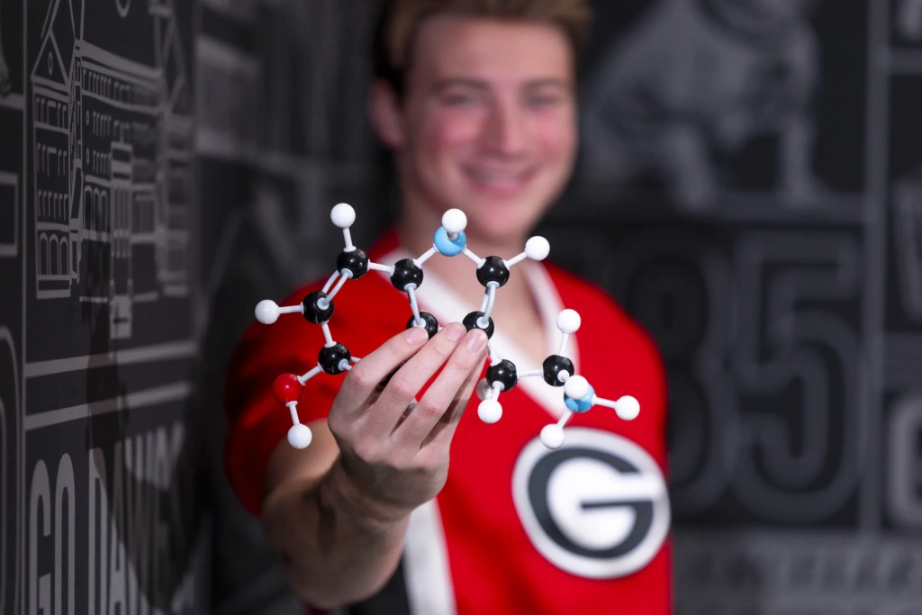 A detail shot of a man holding a plastic model of a molecule.