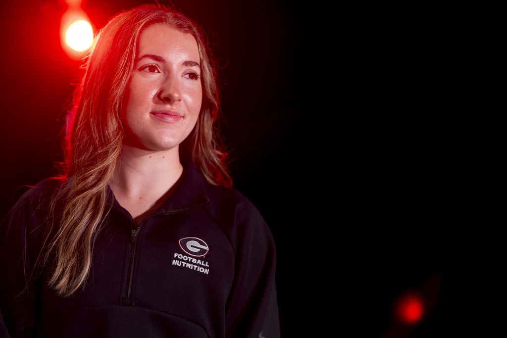 A closeup of a young woman in a dark room. There is a single spotlight just behind her head.